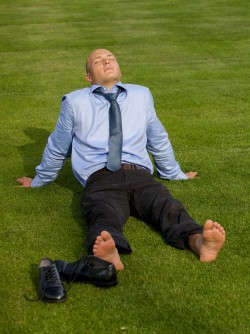 business man with bare feet sitting on grass